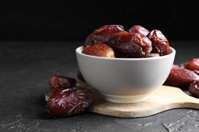 Photo of Tasty dried dates in bowl on grey table