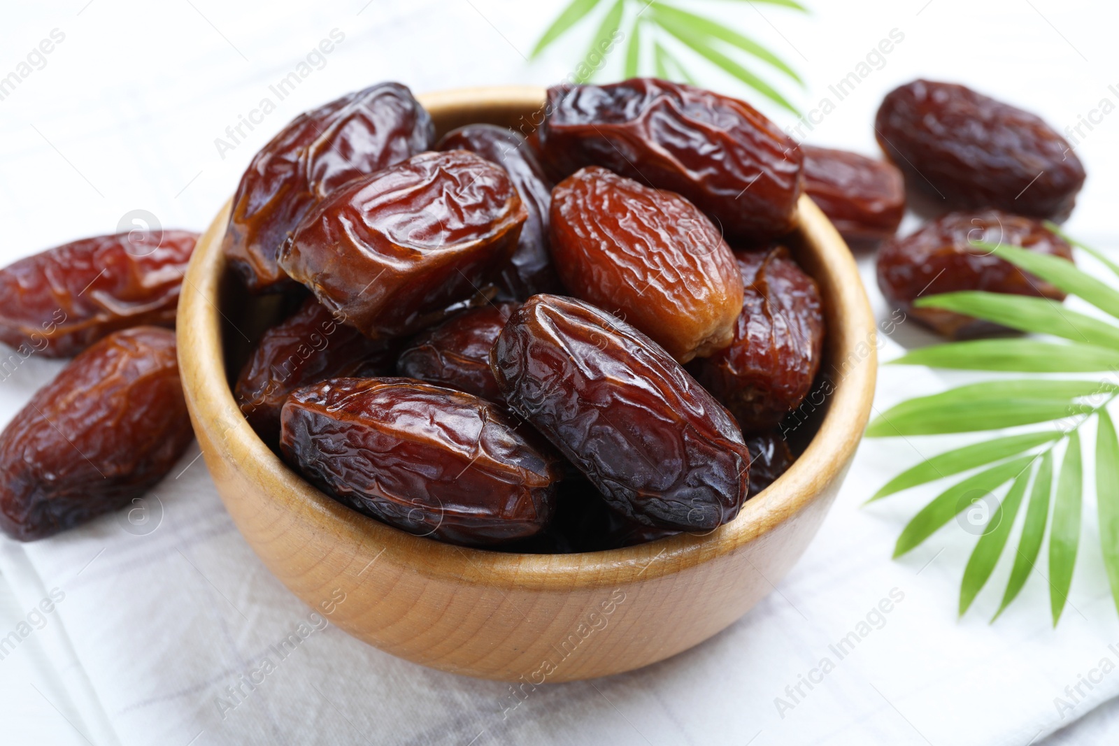 Photo of Tasty dried dates and leaves on white table, closeup