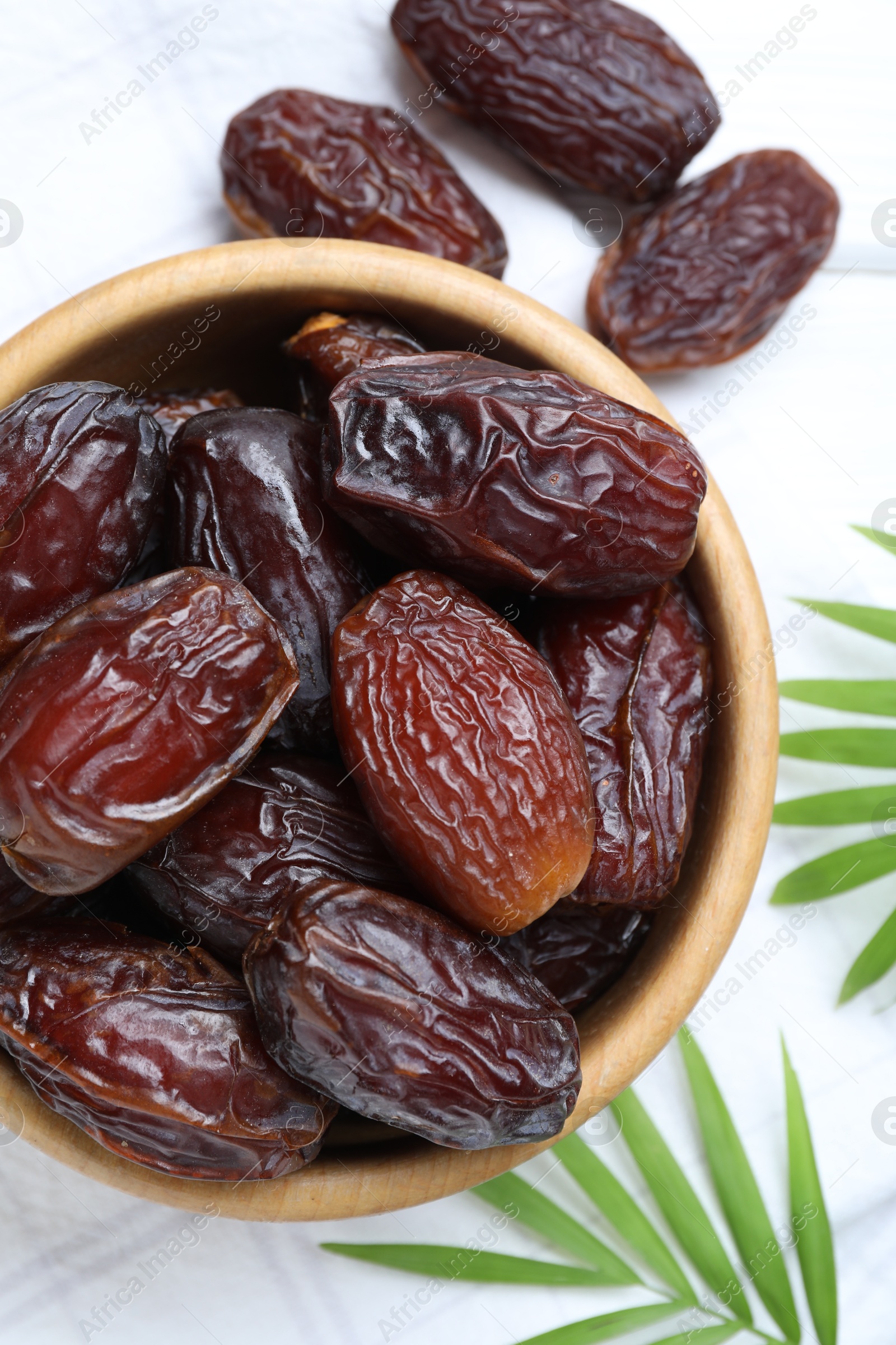 Photo of Tasty dried dates and leaves on white table, flat lay