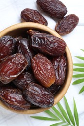 Photo of Tasty dried dates and leaves on white table, flat lay