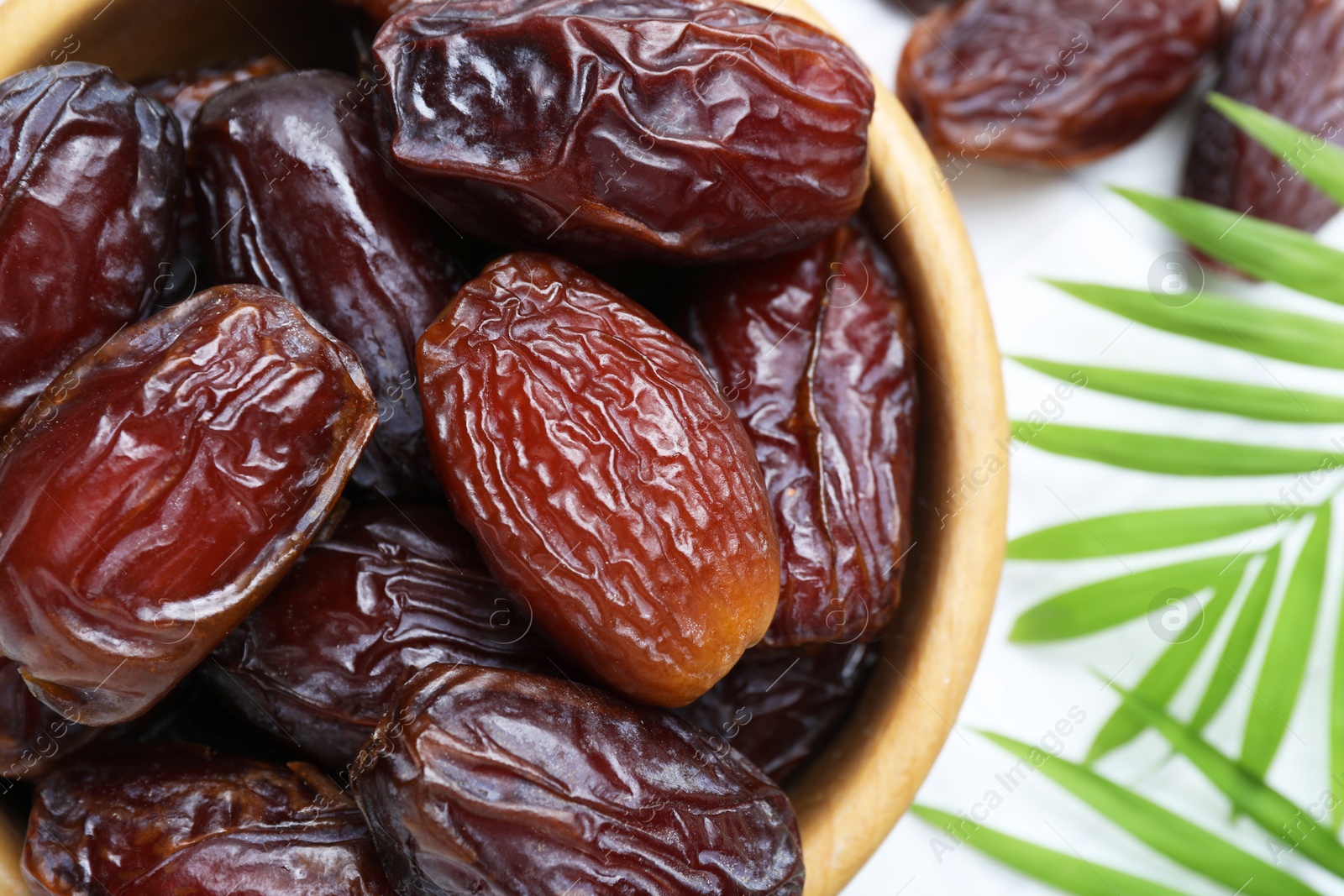 Photo of Tasty dried dates and leaves on white table, top view