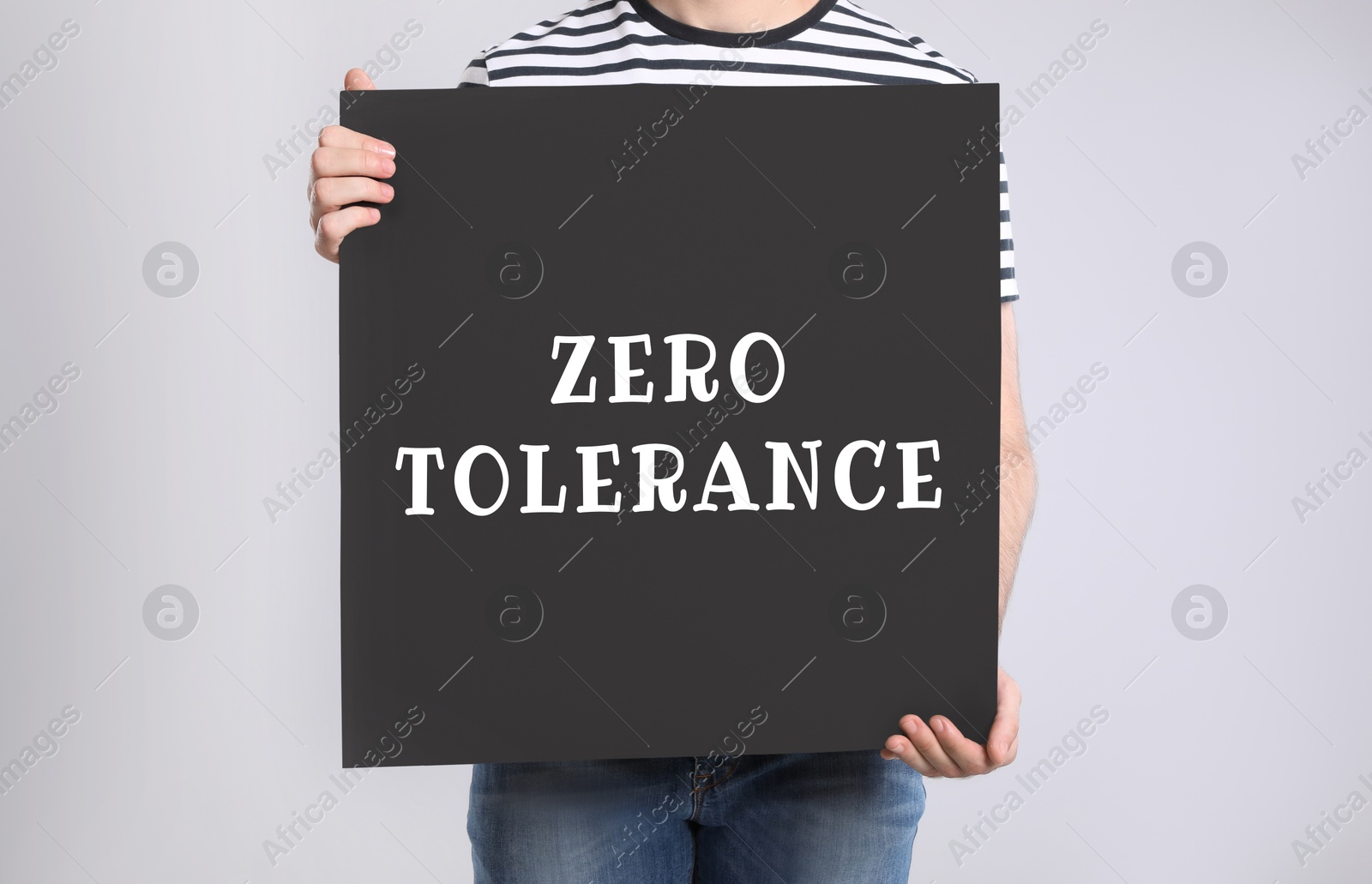 Image of Man holding poster with words Zero Tolerance on light grey background, closeup