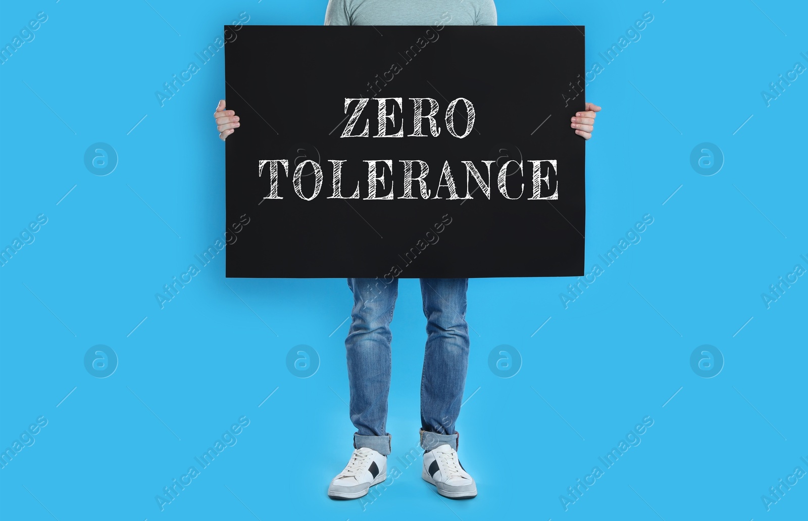 Image of Man holding poster with words Zero Tolerance on blue background, closeup