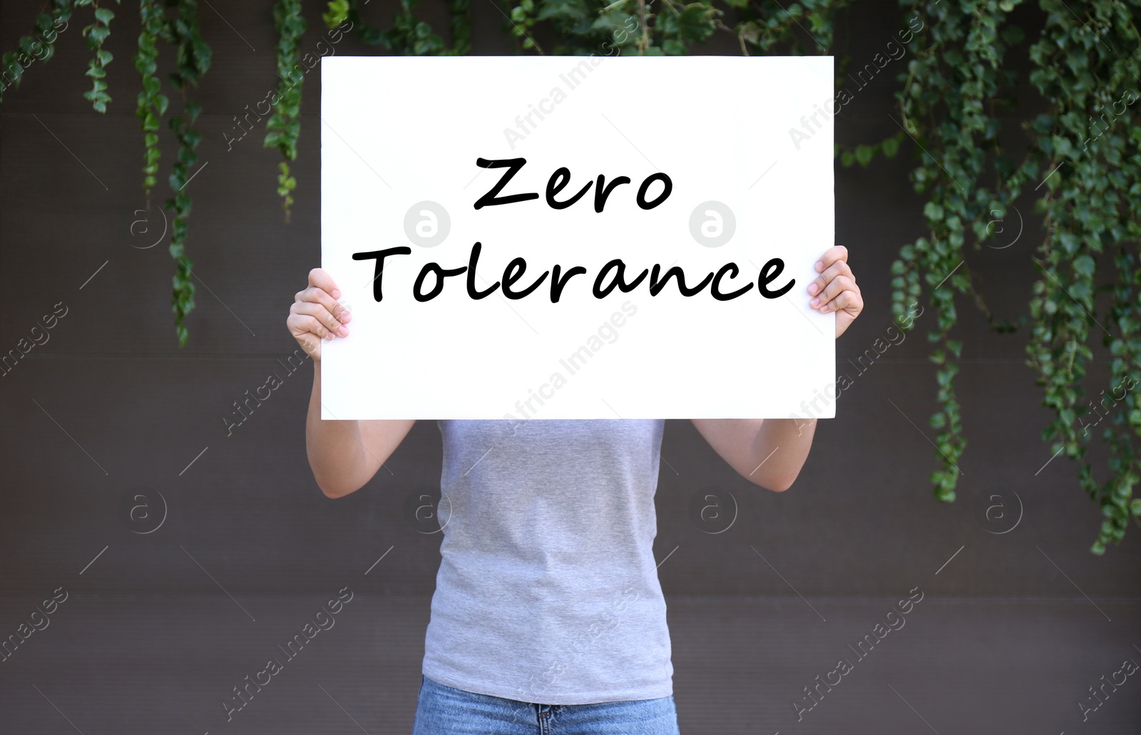 Image of Woman holding poster with words Zero Tolerance outdoors