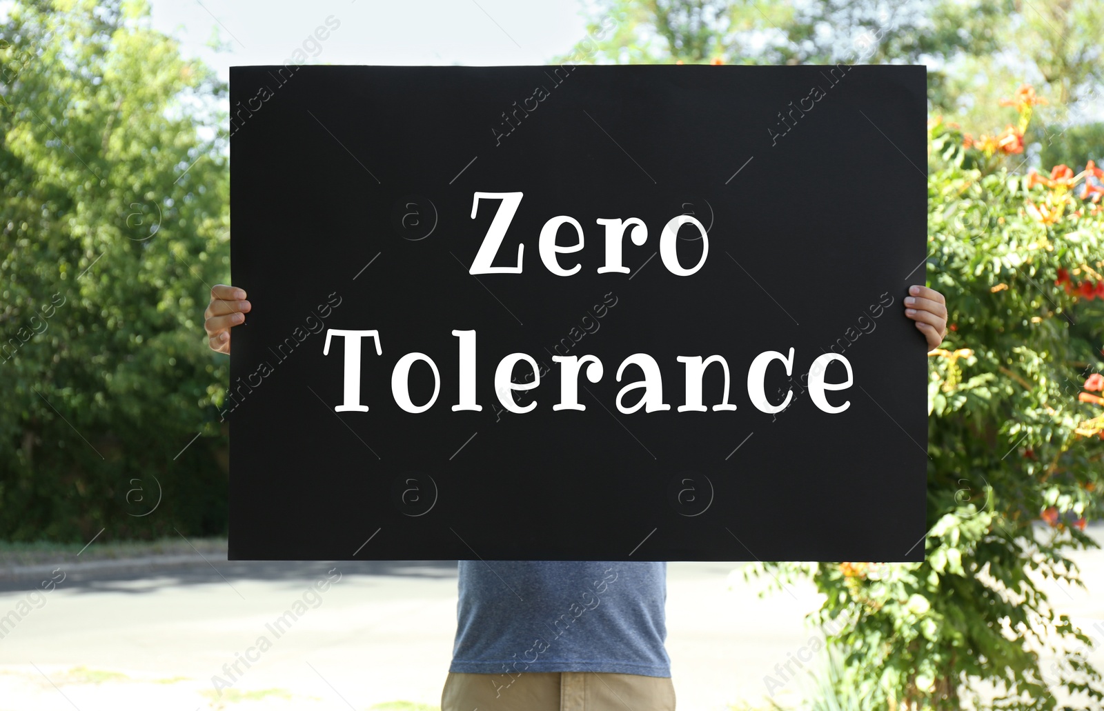 Image of Man holding poster with words Zero Tolerance outdoors