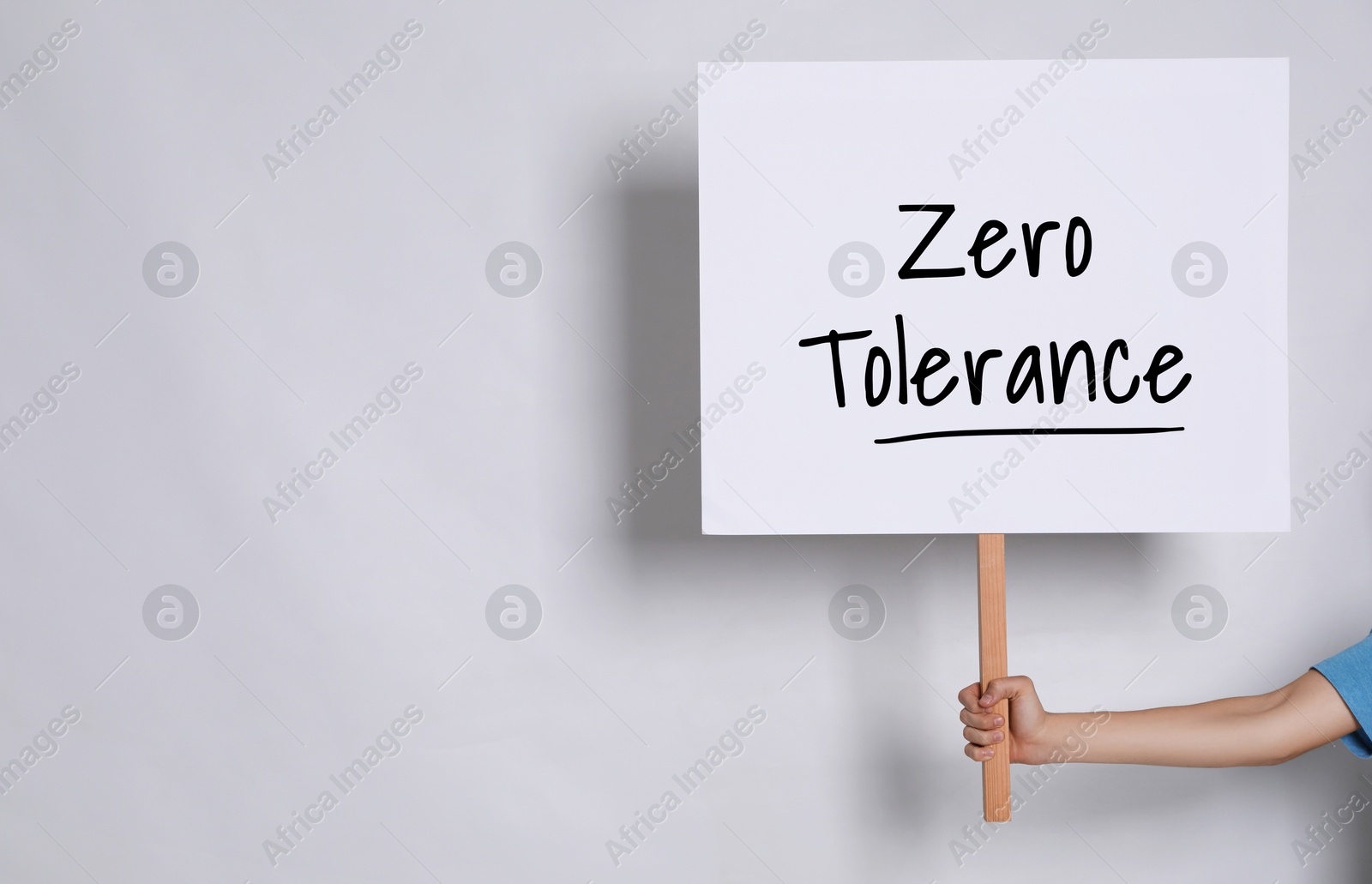 Image of Woman holding sign with words Zero Tolerance on light grey background, closeup. Space for text