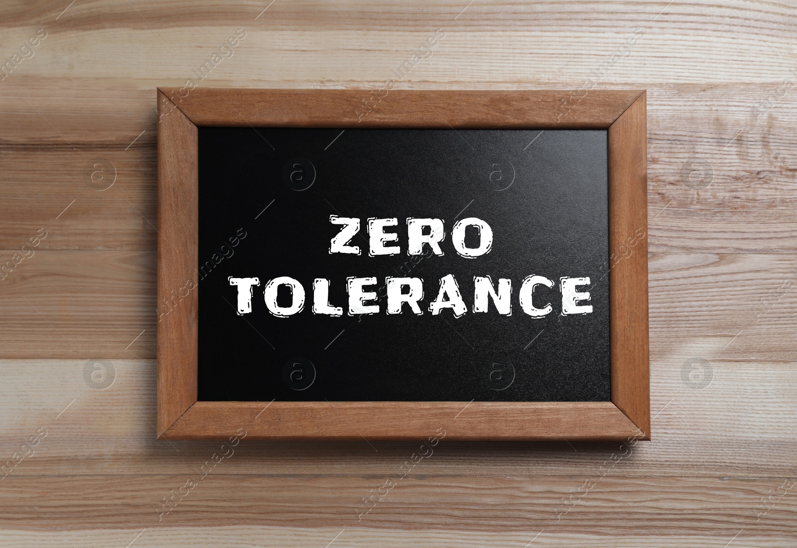 Image of Zero Tolerance concept. Small chalkboard with words on wooden background