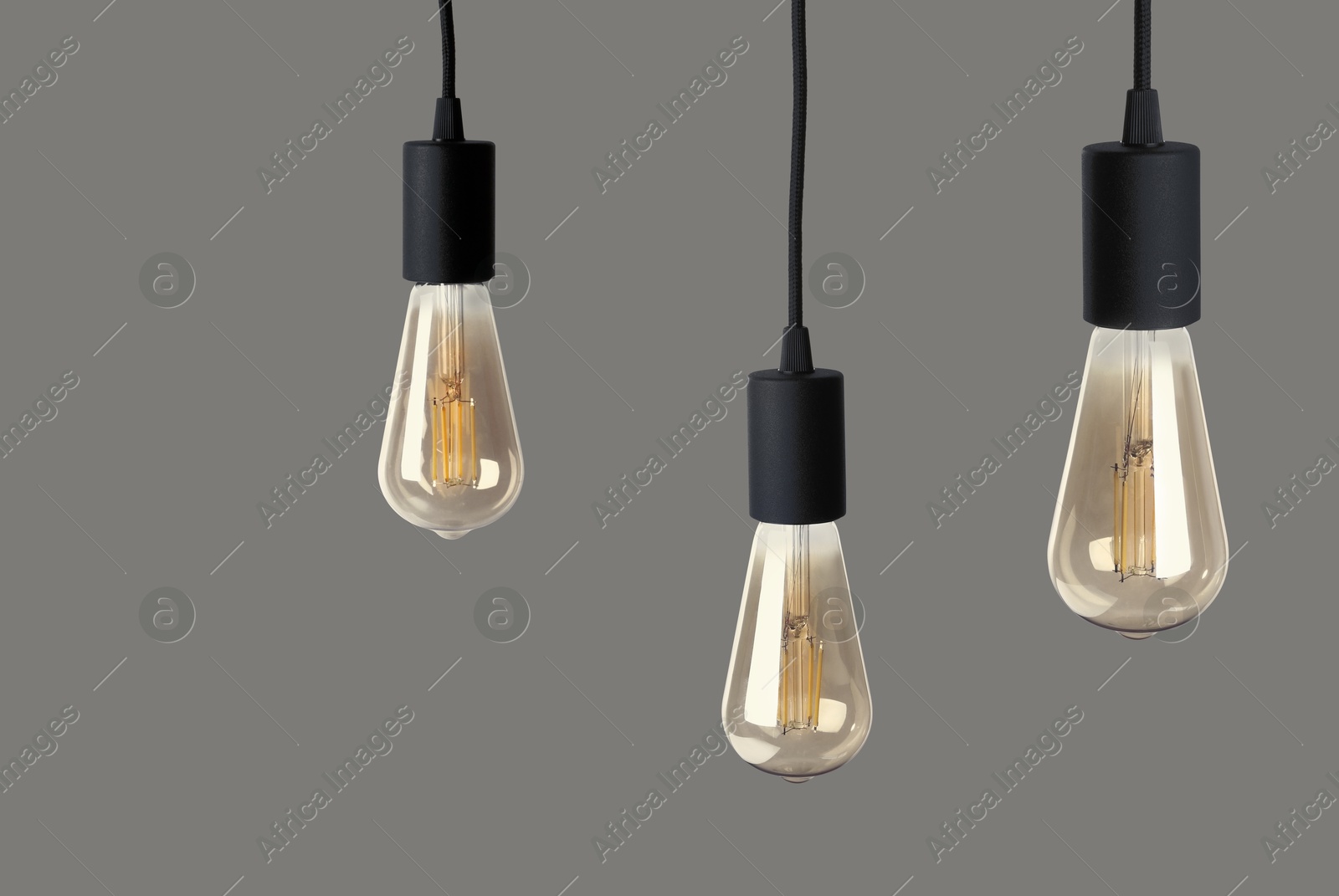 Image of Three light bulbs hanging on grey background