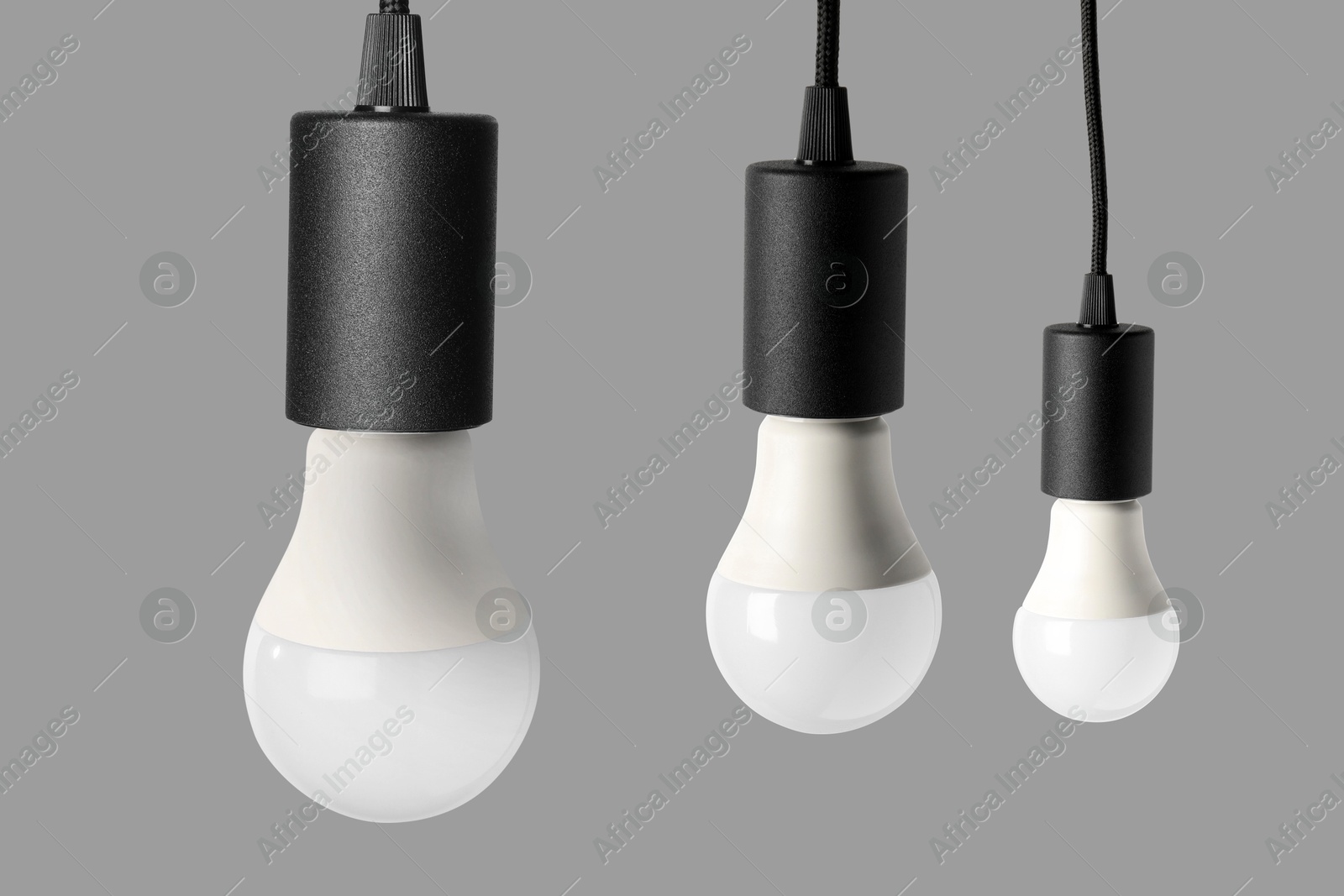 Image of Three light bulbs hanging on grey background