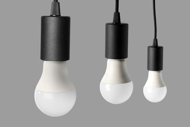 Image of Three light bulbs hanging on grey background