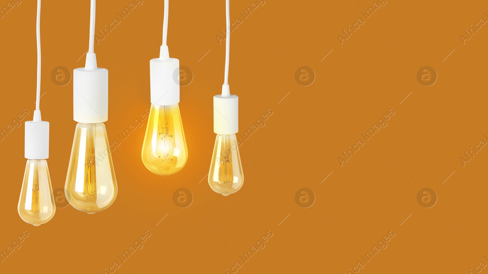 Image of One glowing light bulb among others on ochre color background. Banner design with space for text