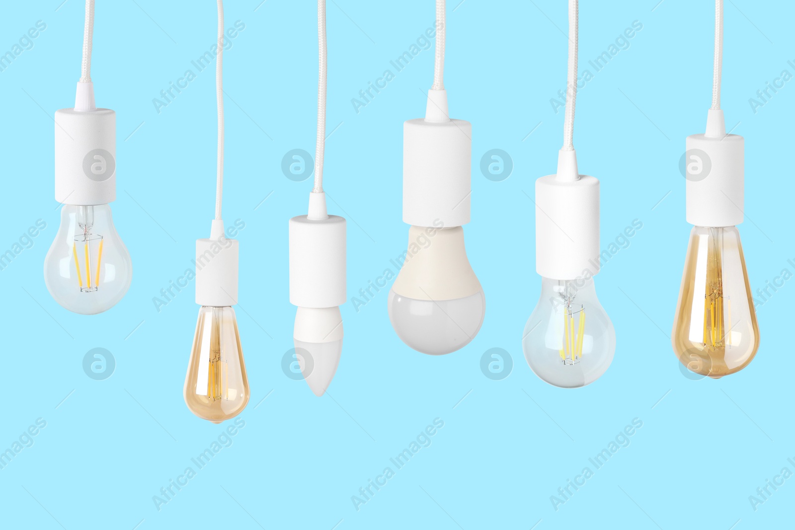 Image of Different light bulbs hanging on light blue background