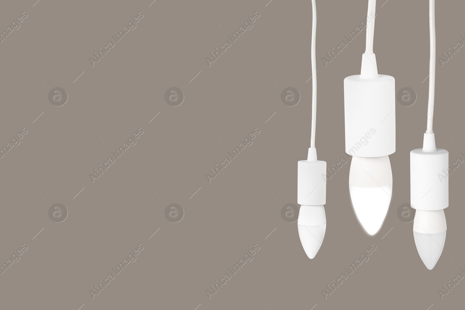 Image of Three light bulbs hanging on beige grey background