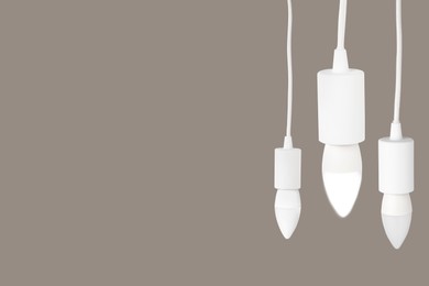 Image of Three light bulbs hanging on beige grey background