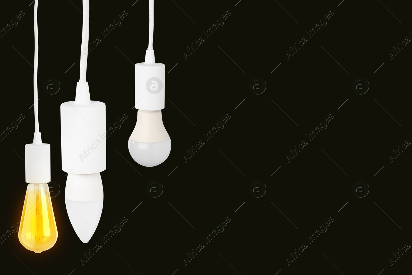 Image of Different light bulbs hanging on black background. Space for text