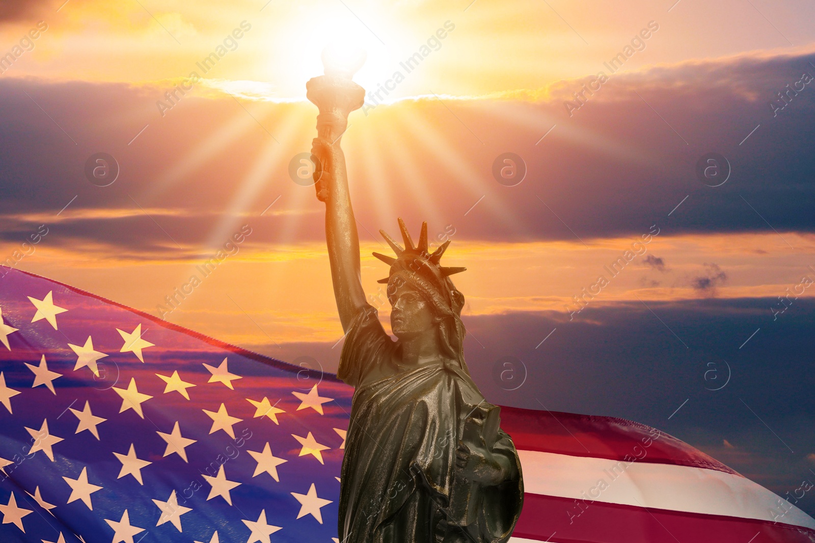 Image of Statue of Liberty against American flag and sunset sky