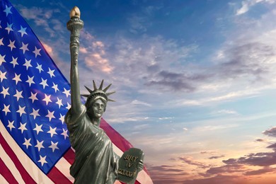 Image of Statue of Liberty against American flag and sunset sky