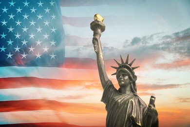 Image of Statue of Liberty against American flag and sunset sky