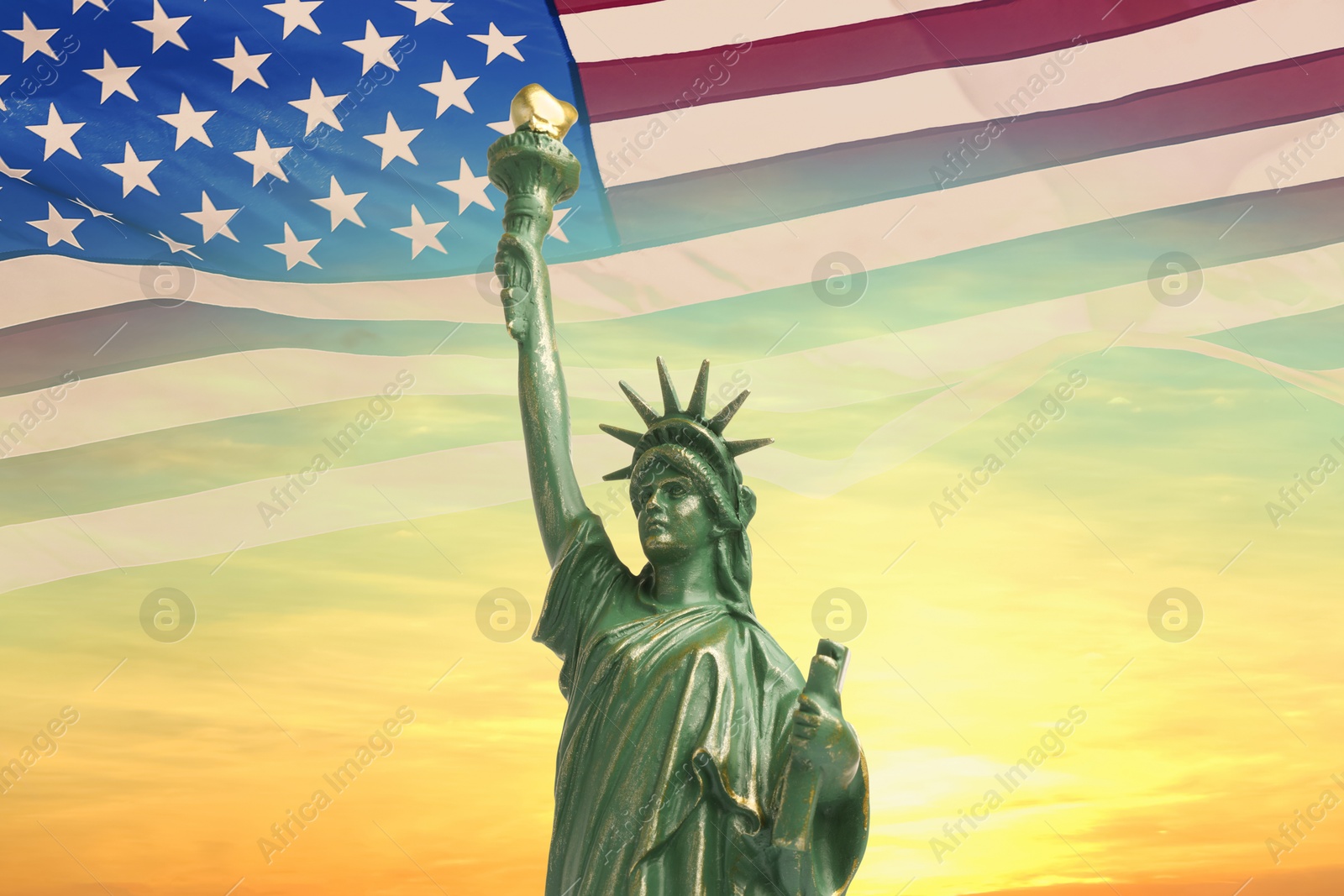 Image of Statue of Liberty against American flag and sunset sky