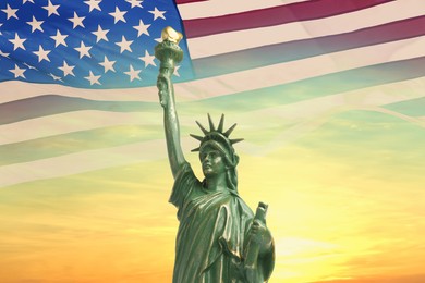 Image of Statue of Liberty against American flag and sunset sky