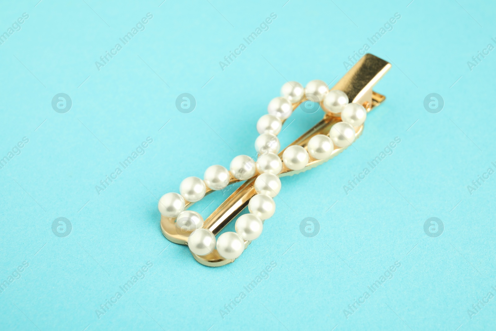 Photo of Beautiful bijouterie. Elegant hair clip on light blue background, closeup