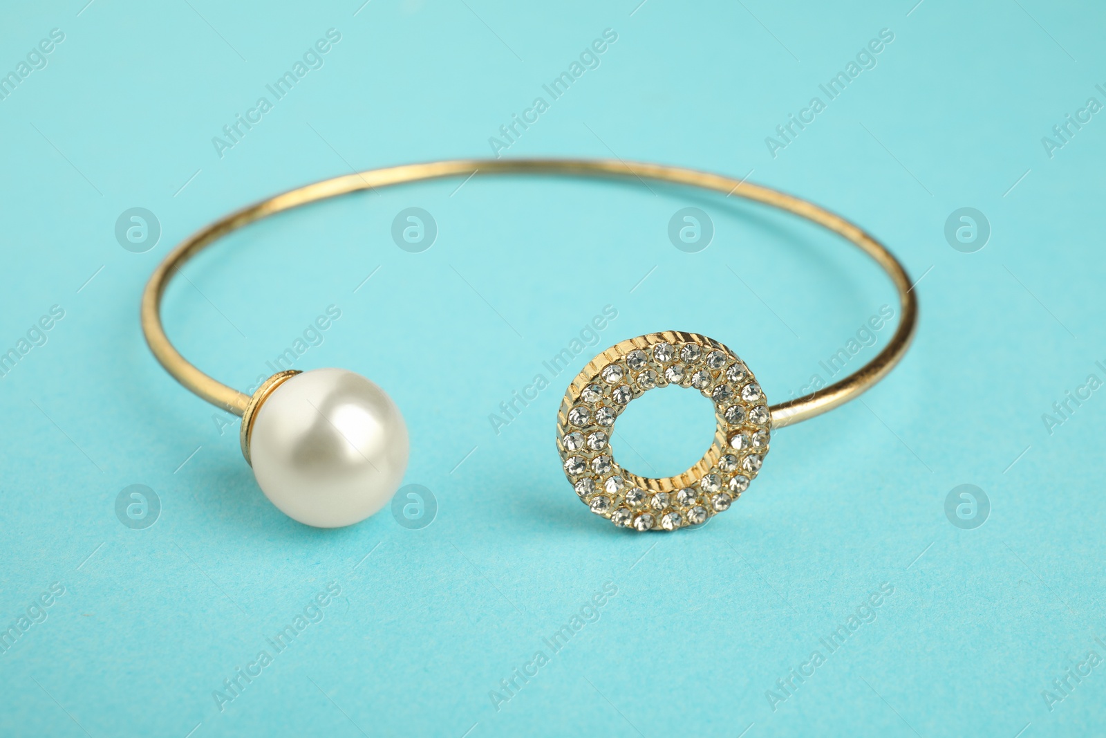 Photo of Beautiful bijouterie. Elegant bracelet on light blue background, closeup