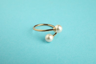 Photo of Beautiful bijouterie. Stylish ring on light blue background, closeup