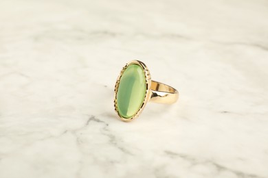 Beautiful bijouterie. Stylish ring on white marble table, closeup