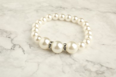 Beautiful bijouterie. Stylish bracelet on white marble table, closeup