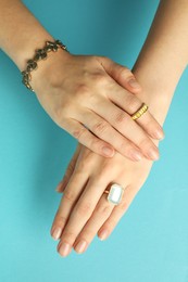 Beautiful bijouterie. Woman wearing different stylish rings and bracelet on light blue background, top view