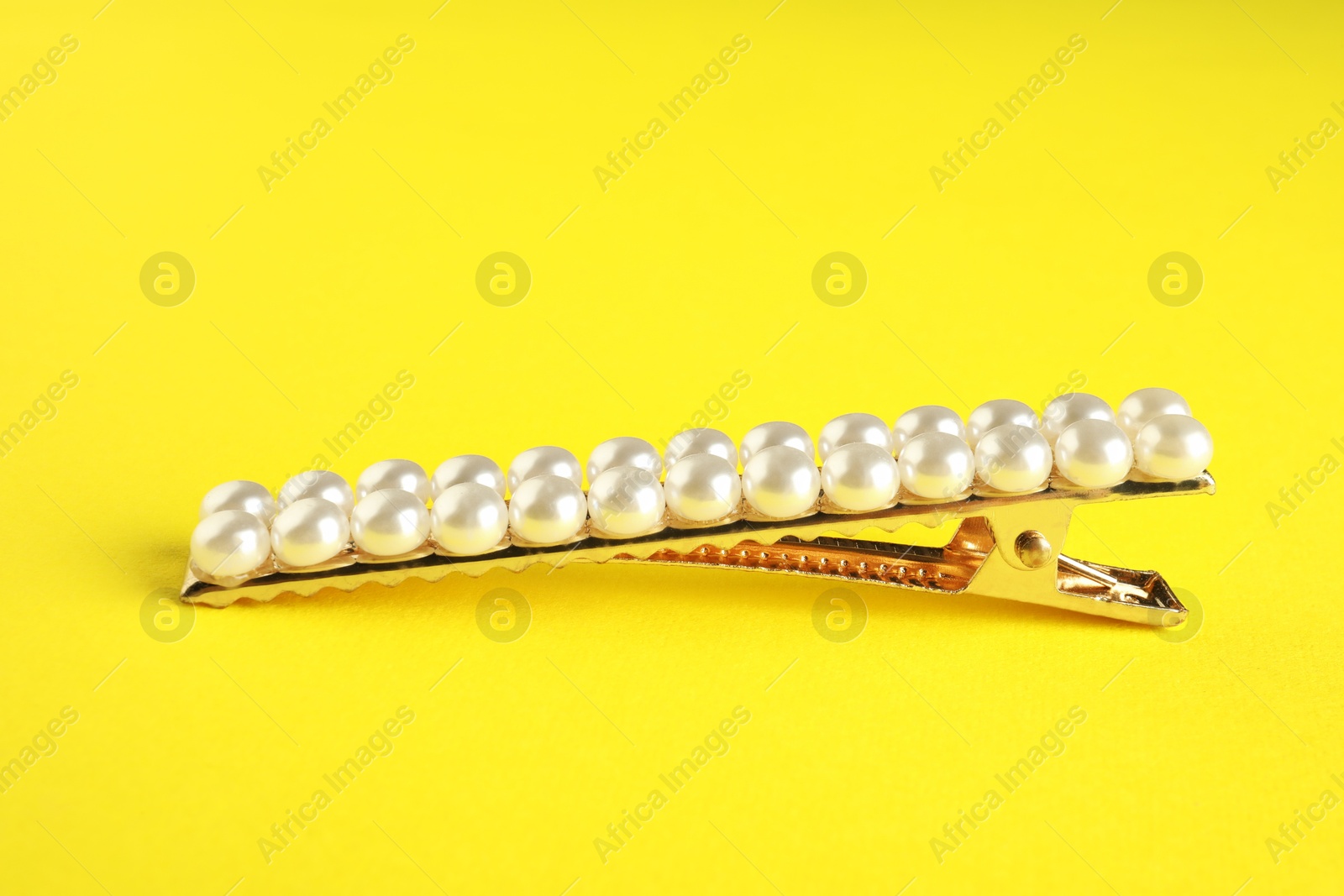 Photo of Beautiful bijouterie. Stylish hair clip on yellow background