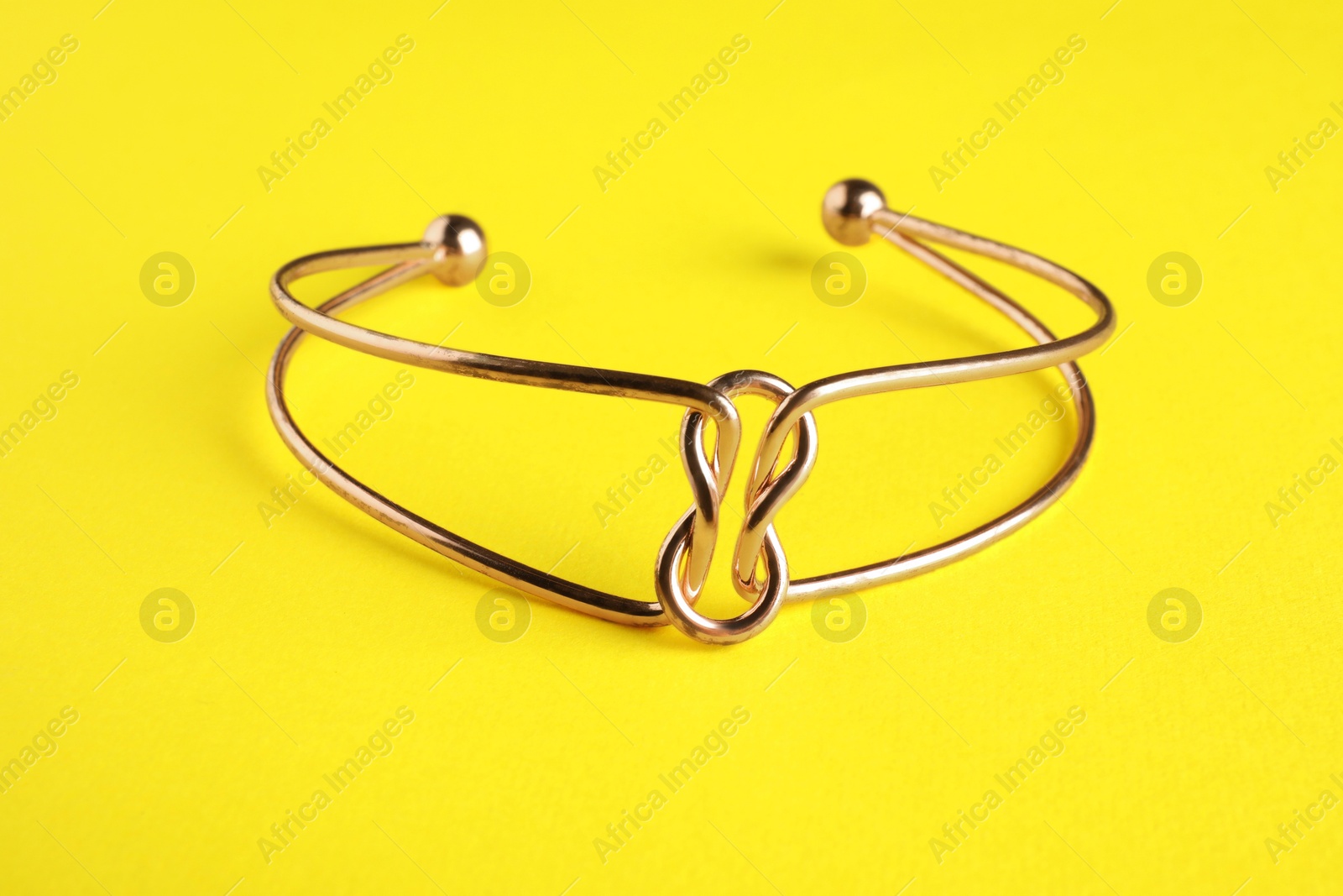 Photo of Beautiful bijouterie. Stylish bracelet on yellow background, closeup