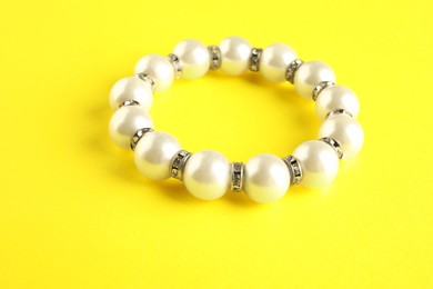 Photo of Beautiful bijouterie. Stylish bracelet on yellow background, closeup