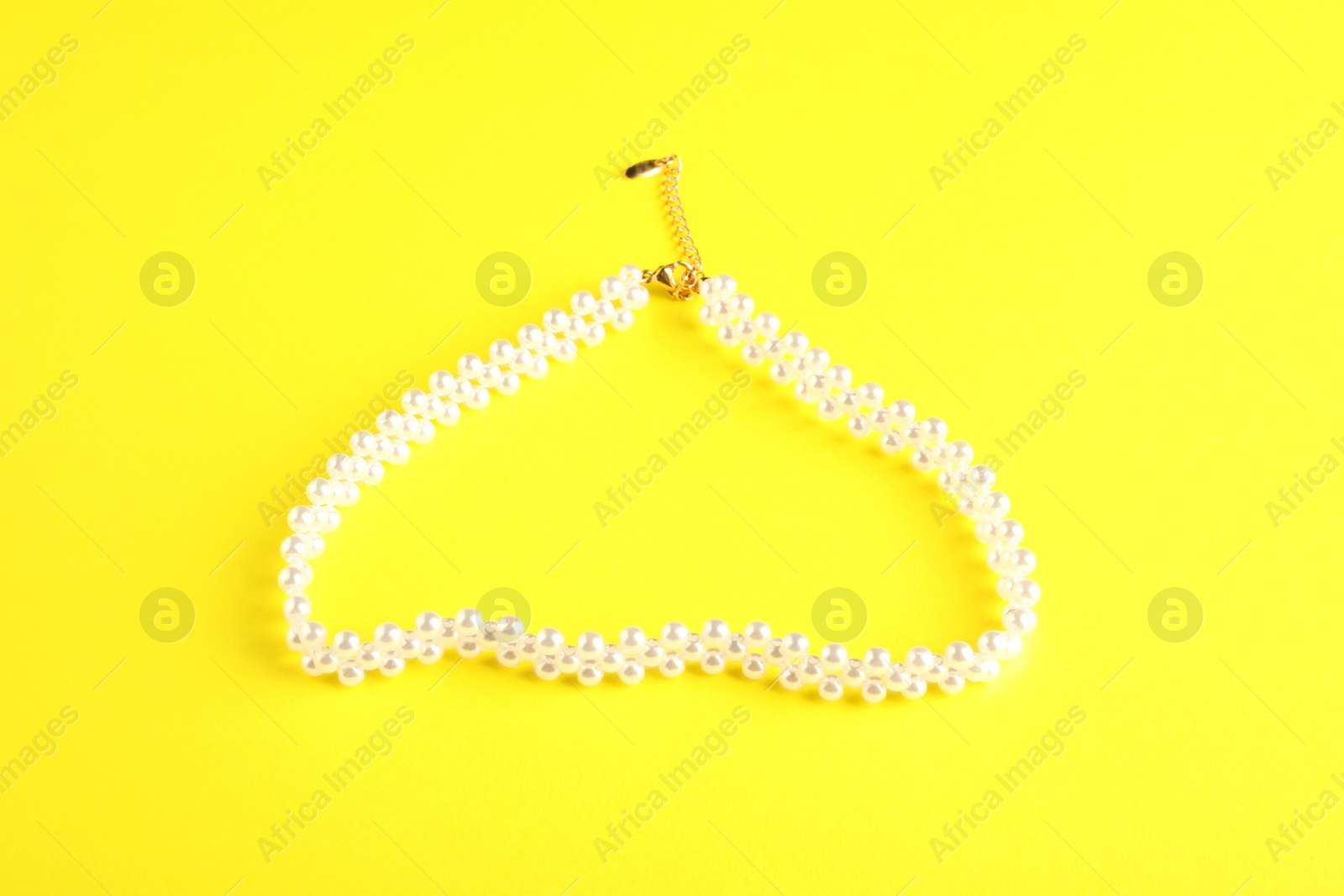 Photo of Beautiful bijouterie. Stylish bracelet on yellow background, top view