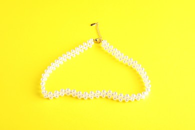 Photo of Beautiful bijouterie. Stylish bracelet on yellow background, top view