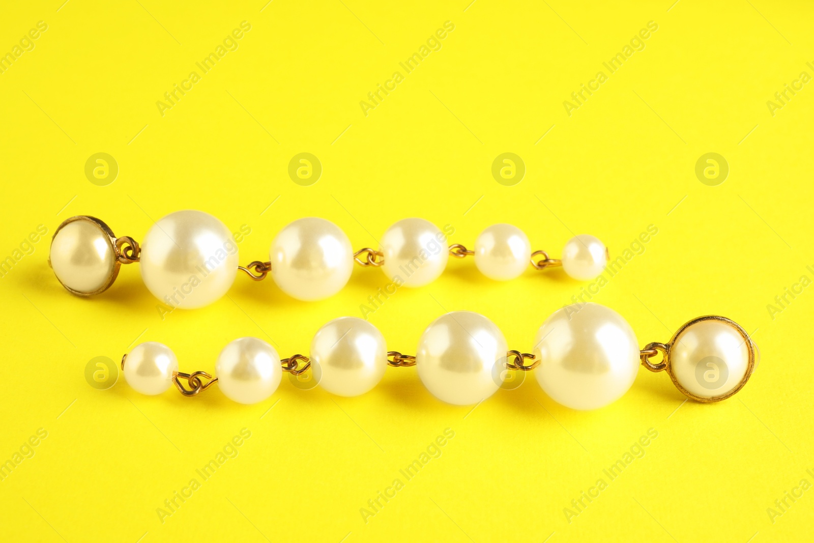 Photo of Beautiful bijouterie. Stylish earrings on yellow background