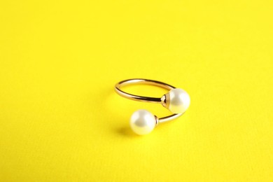 Photo of Beautiful bijouterie. Elegant ring on yellow background, closeup