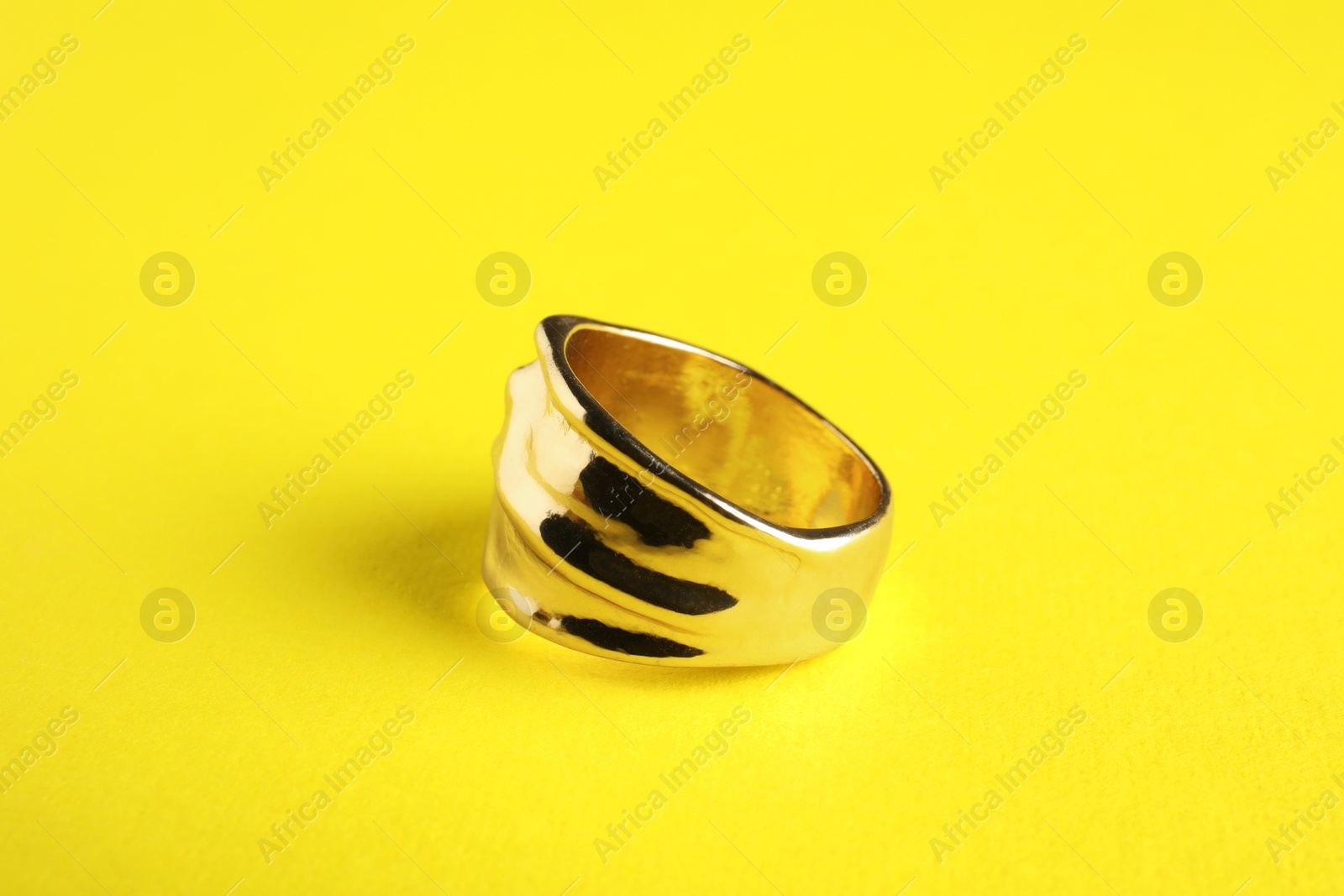 Photo of Beautiful bijouterie. Elegant ring on yellow background, closeup