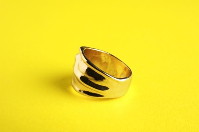 Photo of Beautiful bijouterie. Elegant ring on yellow background, closeup