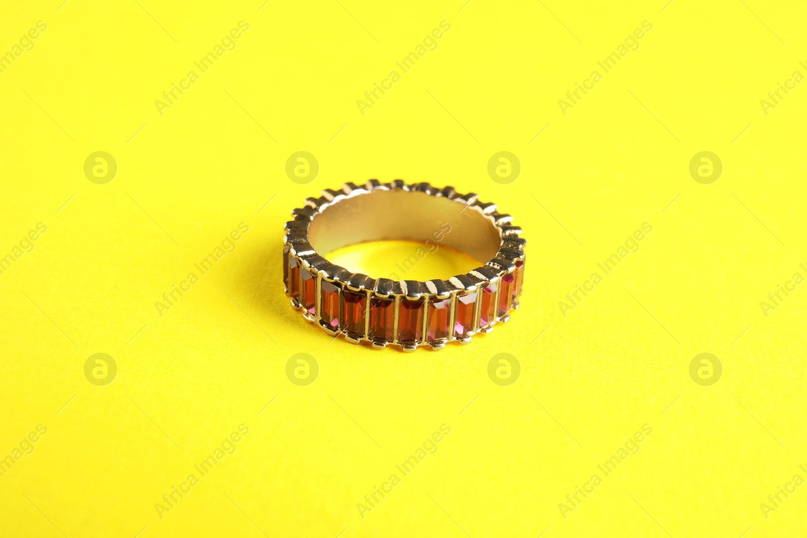 Photo of Beautiful bijouterie. Elegant ring on yellow background, closeup