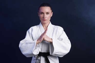 Photo of Karate fighter in kimono on dark background