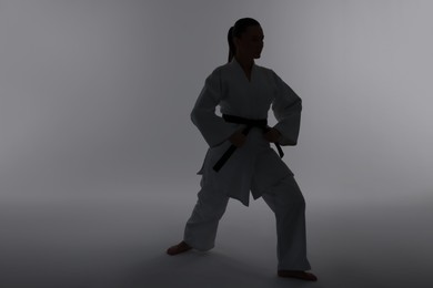 Photo of Silhouette of woman in kimono practicing karate on light background