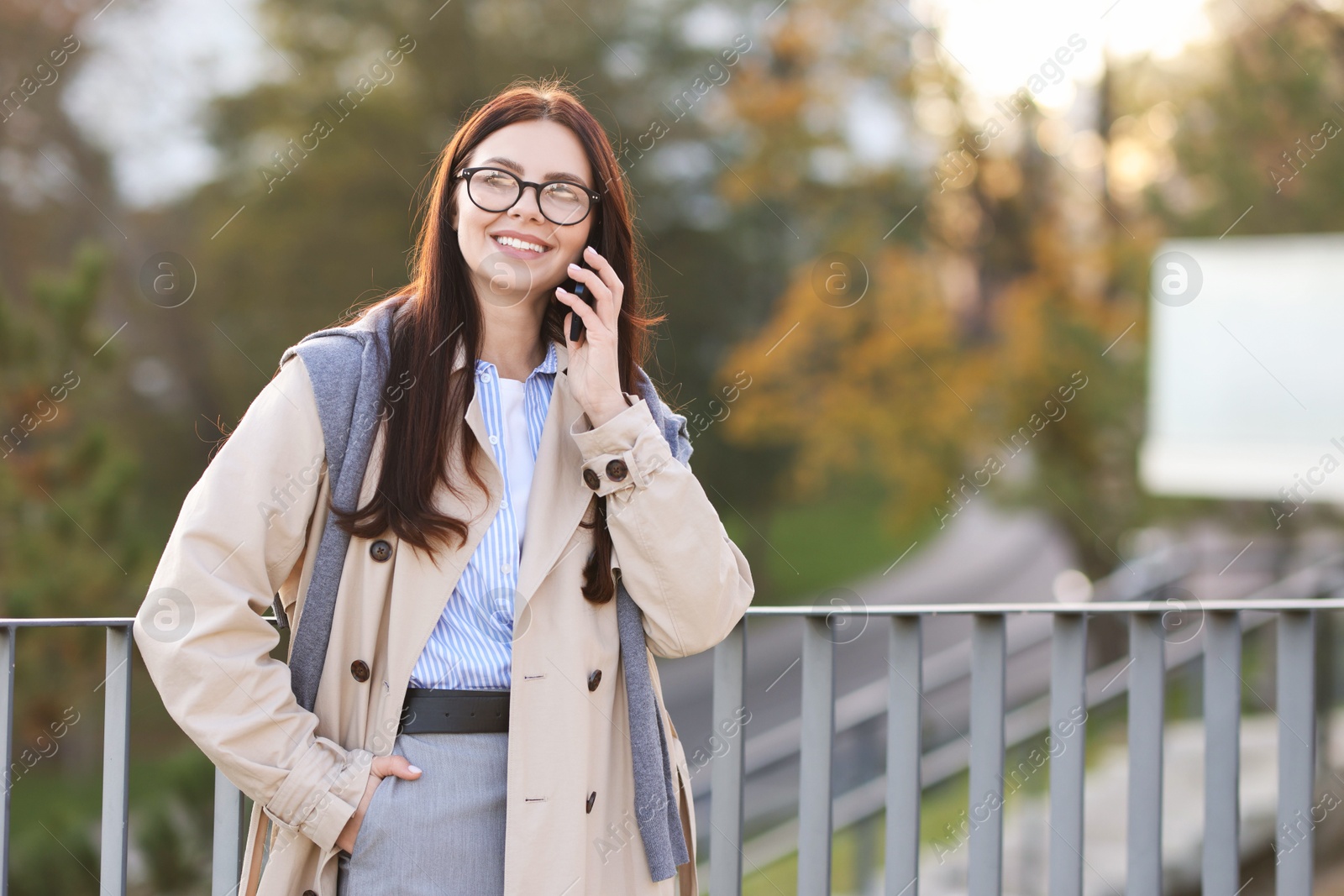 Photo of Beautiful woman in stylish suit talking on smartphone outdoors. Space for text