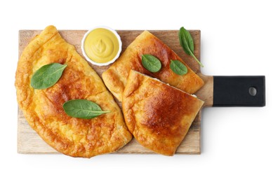 Photo of Tasty calzones with basil and sauce isolated on white, top view