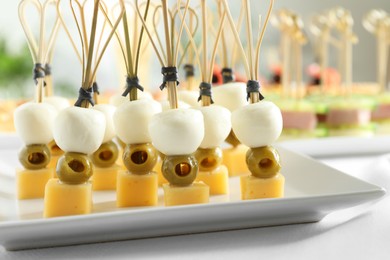 Photo of Tasty canapes with different types of cheese and green olives on white table, closeup