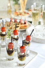 Photo of Many different tasty canapes and wine on white table, closeup