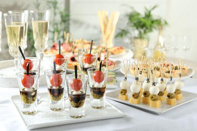 Photo of Many different tasty canapes and wine on white table