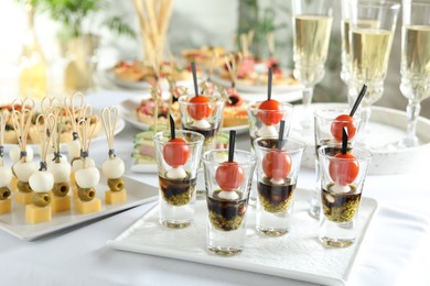 Photo of Many different tasty canapes and wine on white table