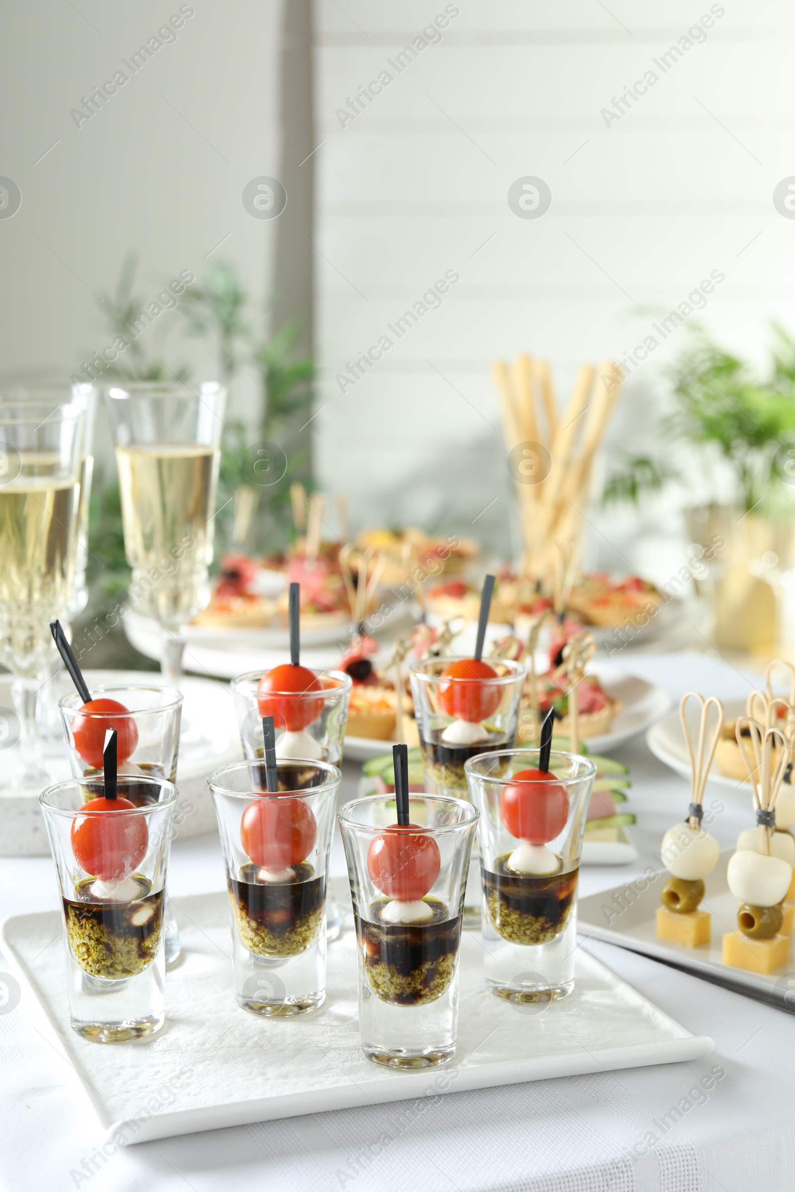 Photo of Many different tasty canapes and wine on white table