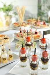 Photo of Many different tasty canapes on white table